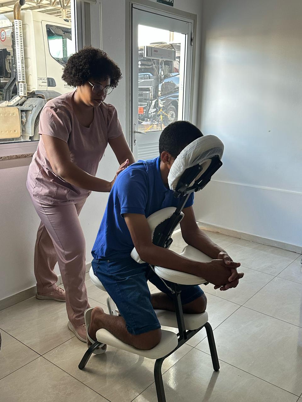 Gisele realizando quick massage na cadeira em uma empresa